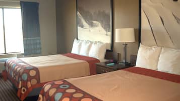 A hotel room with two beds, a large window with curtains, a painting on the wall, and a lamp on the nightstand.