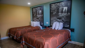 Une chambre d’hôtel avec deux lits, chacun recouvert d’une couvre-lit à motifs et agrémenté de coussins blancs. Deux grandes images encadrées représentant des cascades ornent le mur.