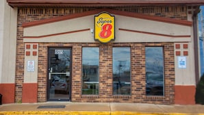 Un motel Super 8 avec une façade en briques, de grandes fenêtres et une enseigne « Super 8 » bien visible.
