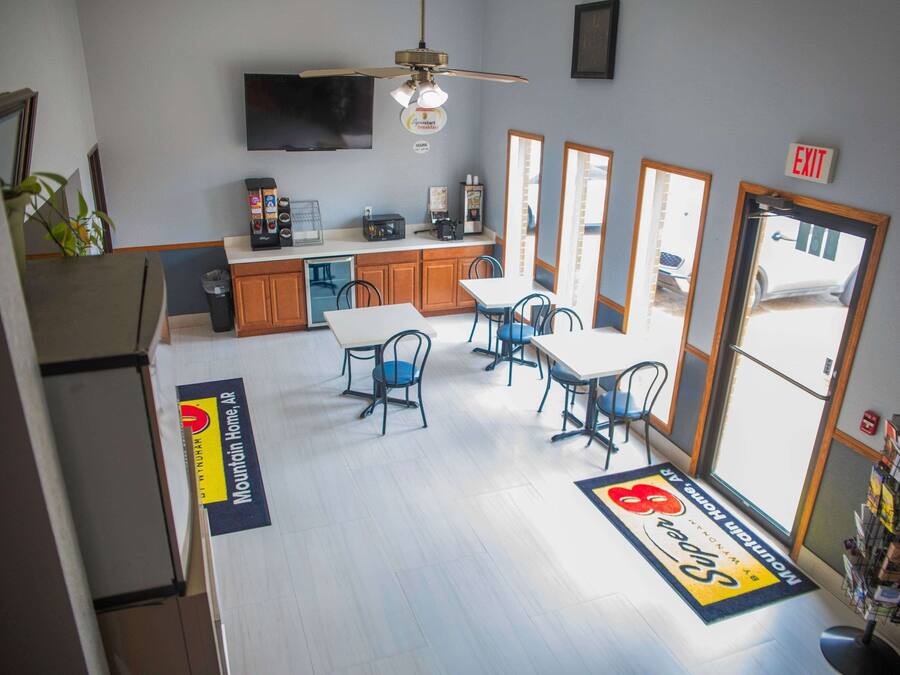 A hotel lobby with a reception desk, a coffee machine, and a seating area with tables and chairs.
