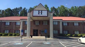 A brick building with a red roof and a sign reading "HAVEN INN & SUITES." - Haven Inn & Suites (Monroe)