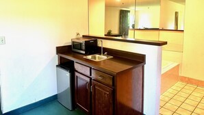 A compact kitchen with a microwave, sink, and dishwasher. - Haven Inn & Suites (Monroe)