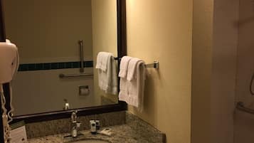 Une salle de bain avec un lavabo en granit, un miroir et deux serviettes suspendues à un porte-serviettes.