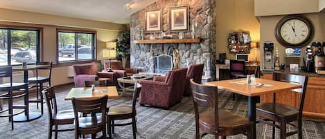 A cozy hotel lobby with a stone fireplace, comfortable seating, and a bar area.