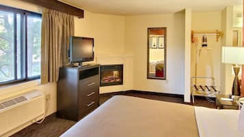 A hotel room with a bed, a television, a dresser, a mirror, and a window with curtains.
