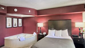 Quarto de hotel com uma cama grande, uma banheira separada e uma pequena escrivaninha com abajur.