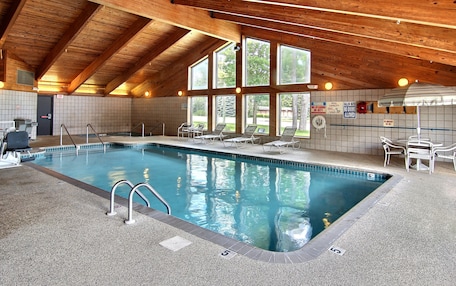 An indoor swimming pool with a wooden ceiling and large windows.