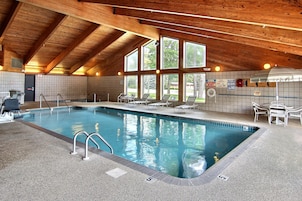 An indoor swimming pool with a wooden ceiling and large windows.