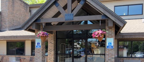 A building with a brick facade, a covered entrance, and hanging flower baskets.