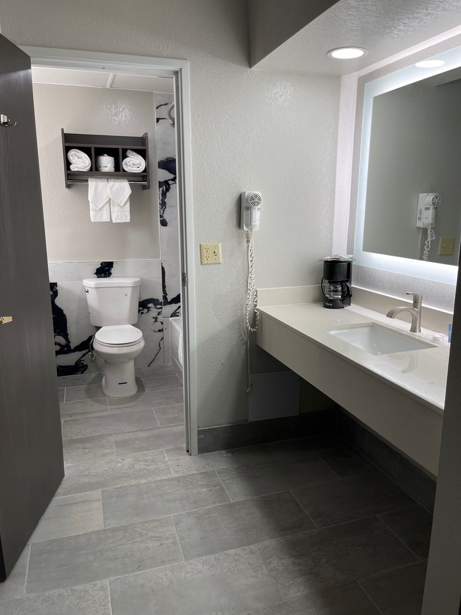 A modern bathroom with a toilet, sink, and hairdryer.