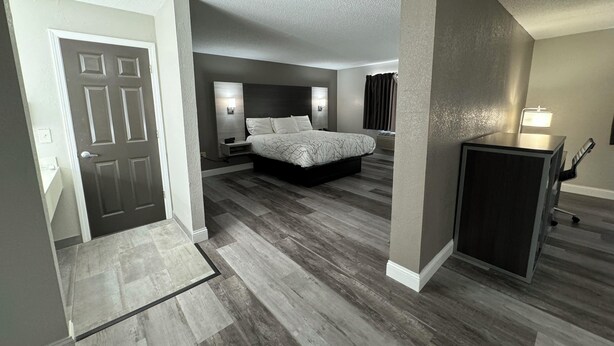 A modern bedroom with a large bed, a desk, and a chair. - HomeTown Inn & Suites (Belle Plaine)