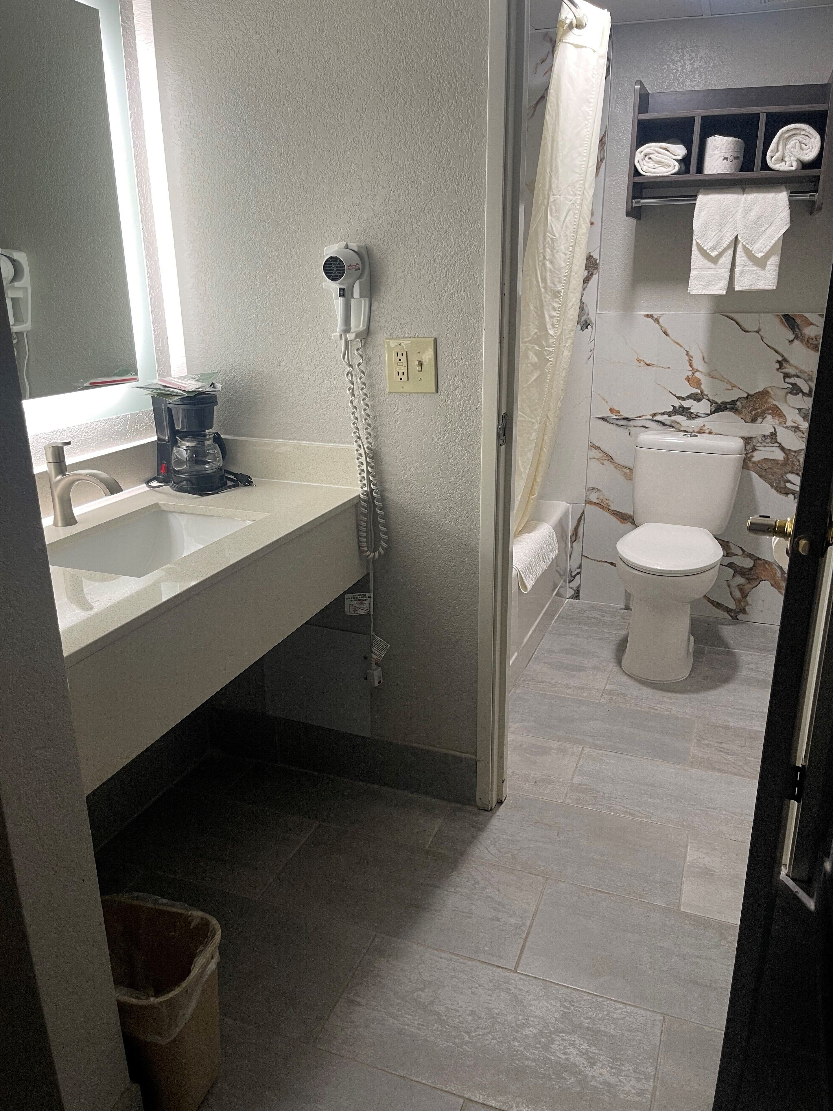 A bathroom with a sink, a shower, a toilet, and a towel rack.