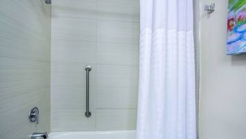 Une salle de bain moderne équipée d’une baignoire, d’une douche et d’une barre d’appui.