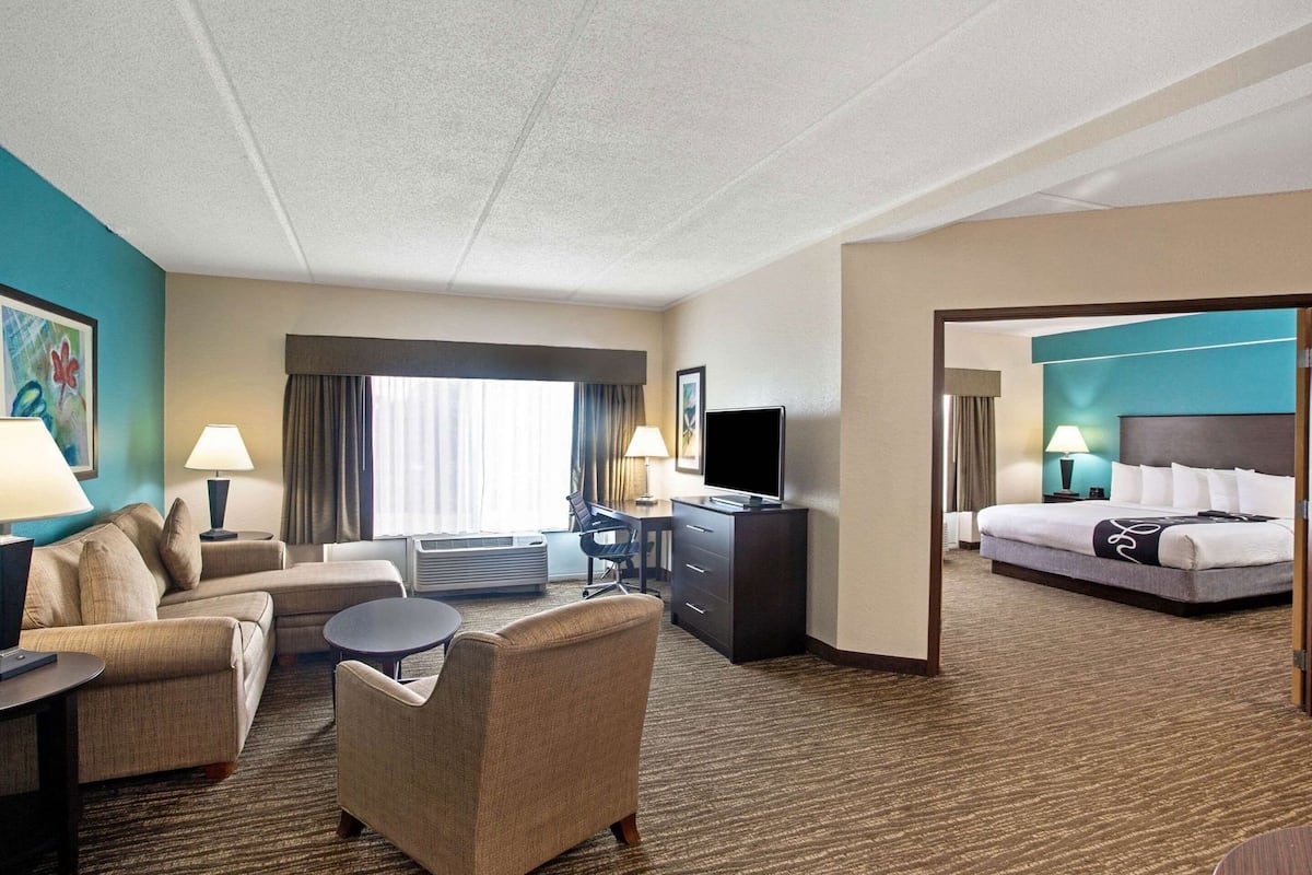 Habitación de hotel con cama, escritorio, silla, televisor y ventana.