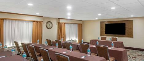 A conference room with tables and chairs, equipped with water bottles and pens.