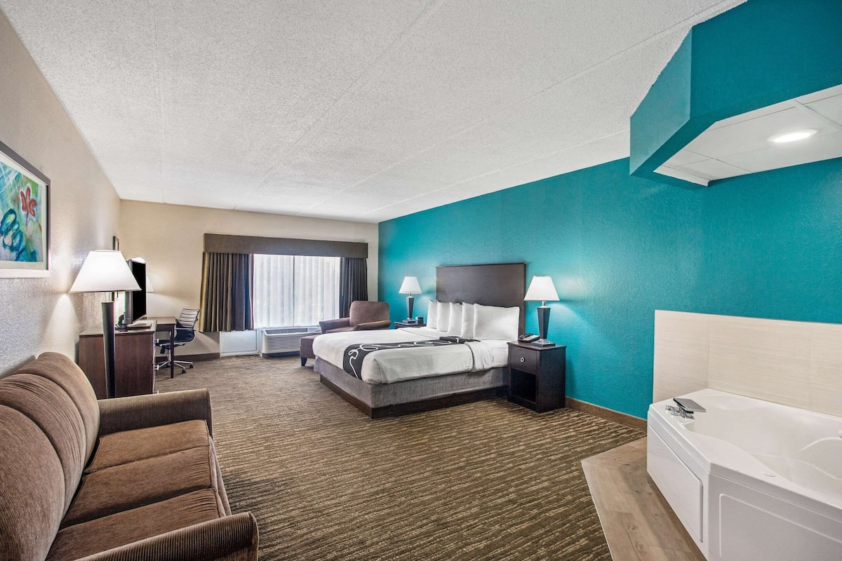 Habitación de hotel con cama, sofá, escritorio y baño.