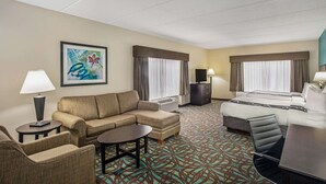 Una habitación de hotel con sofá, cama, escritorio y televisor.