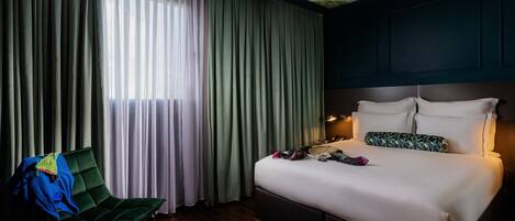 Una habitación de hotel con una cama, una silla, un escritorio y una ventana con cortinas.