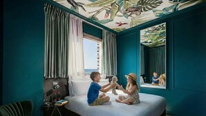 Ein Zimmer mit Bett, Fenster, Vorhängen, Lampe und Stuhl.