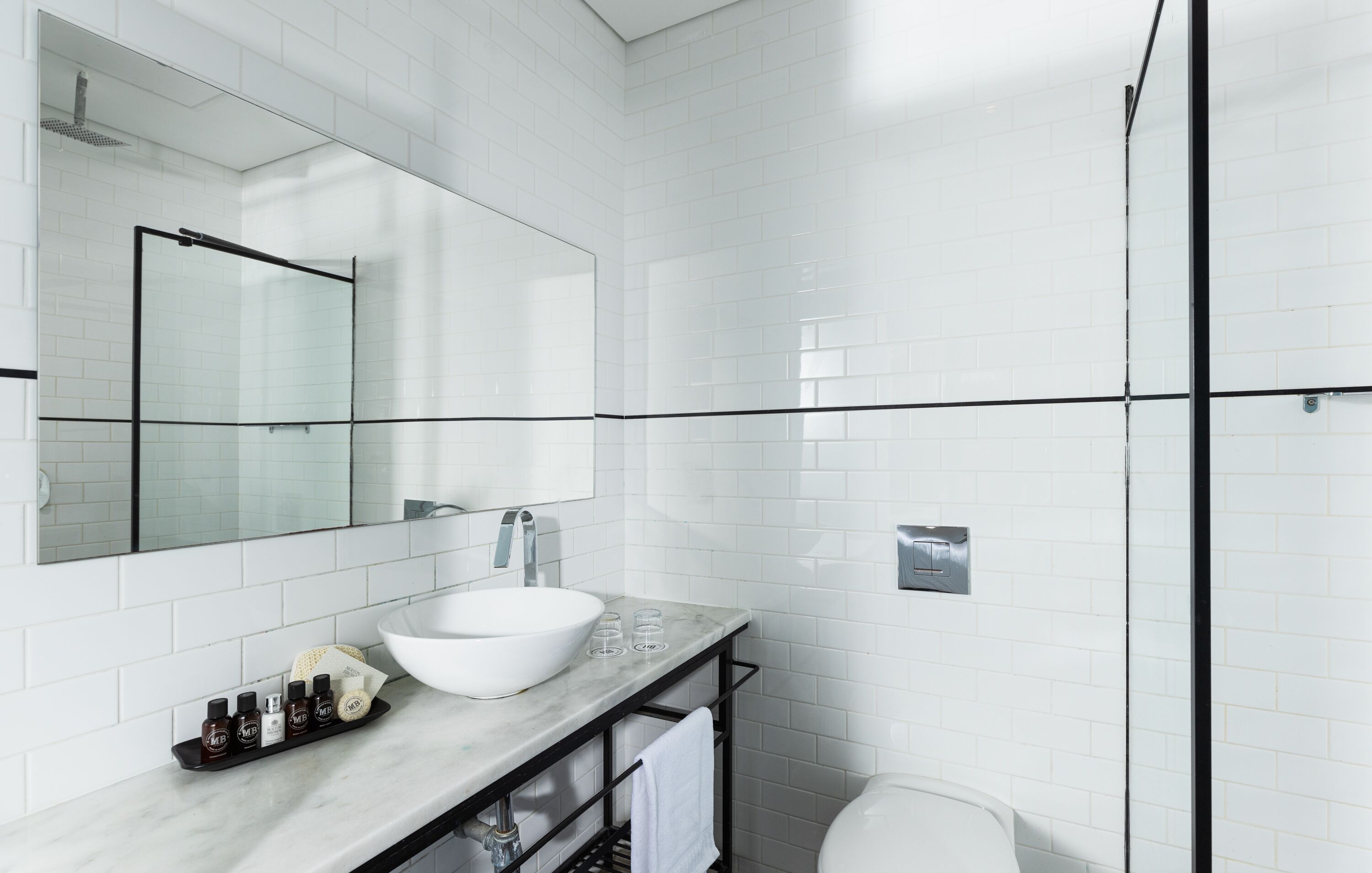 A modern bathroom with a white sink, large mirror, and a glass-enclosed shower.