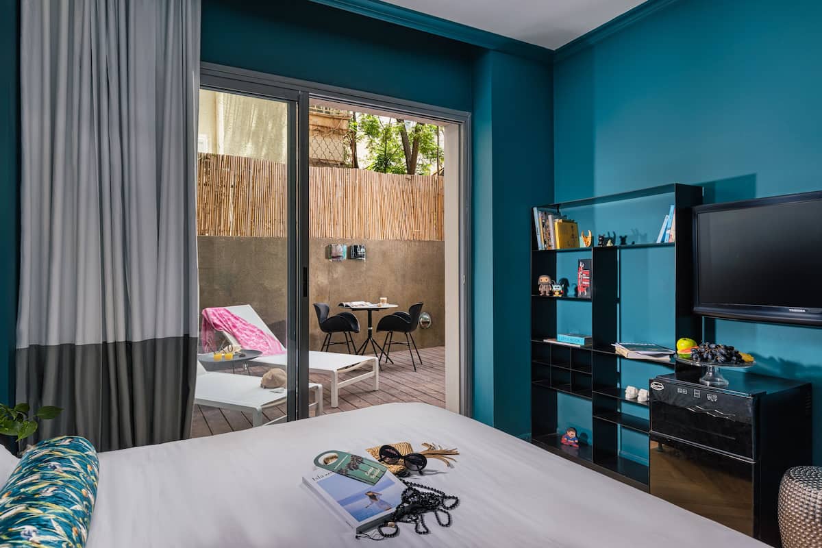 Une chambre d’hôtel comprenant un lit, une télévision, un bureau avec une chaise et un balcon avec une table et des chaises.
