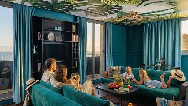 Ein modernes Wohnzimmer mit türkisfarbenen Sofas, einem Couchtisch und einem Bücherregal.