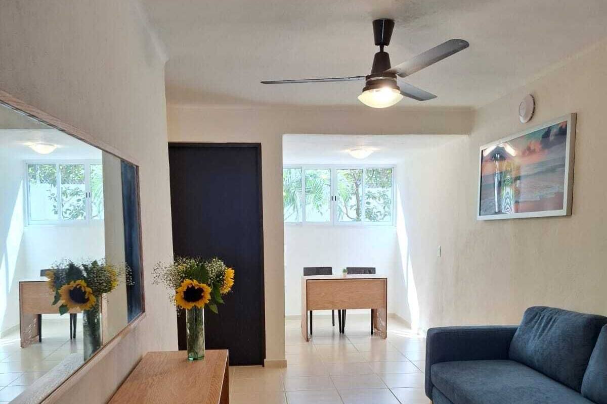 A living room with a sofa, a wooden table, and a ceiling fan.