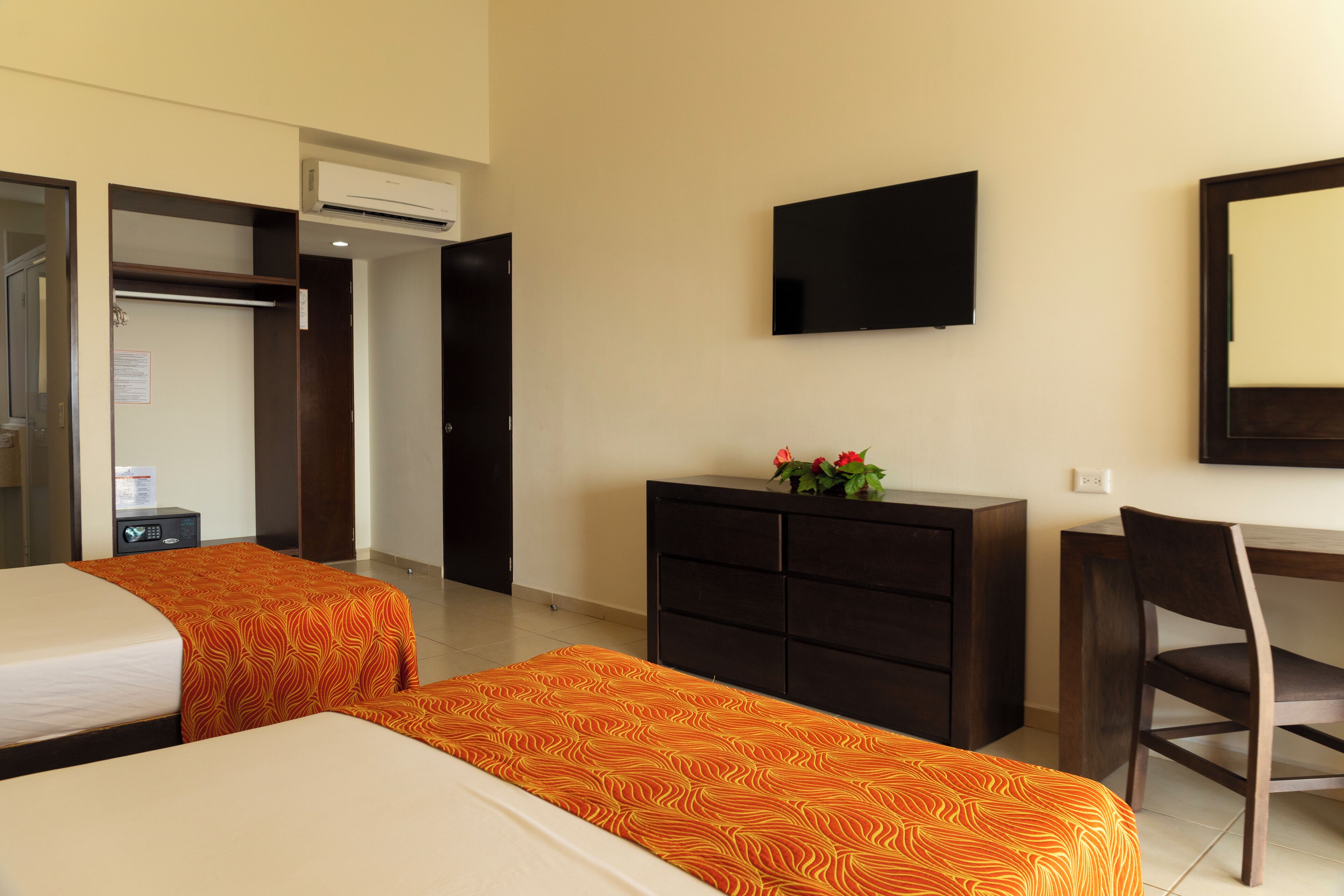 Une chambre d’hôtel avec deux lits, un bureau, une chaise, une télévision et une commode.