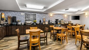 Un restaurante con mesas y sillas de madera, una pared de ladrillo y un televisor de pantalla plana montado en la pared.