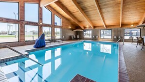 Una piscina interior con vigas de madera y grandes ventanales.