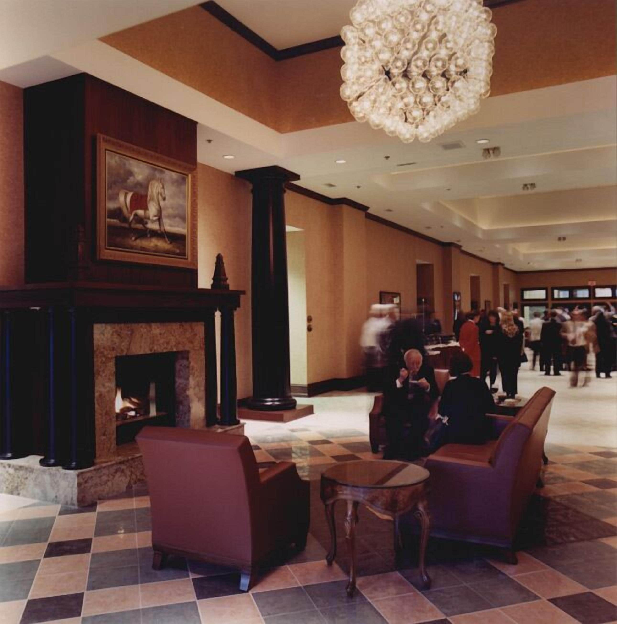 A hotel lobby with a fireplace, seating area, and a large chandelier.