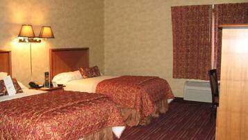 A hotel room with two beds, a wooden headboard, a telephone, a nightstand, and a window with curtains.