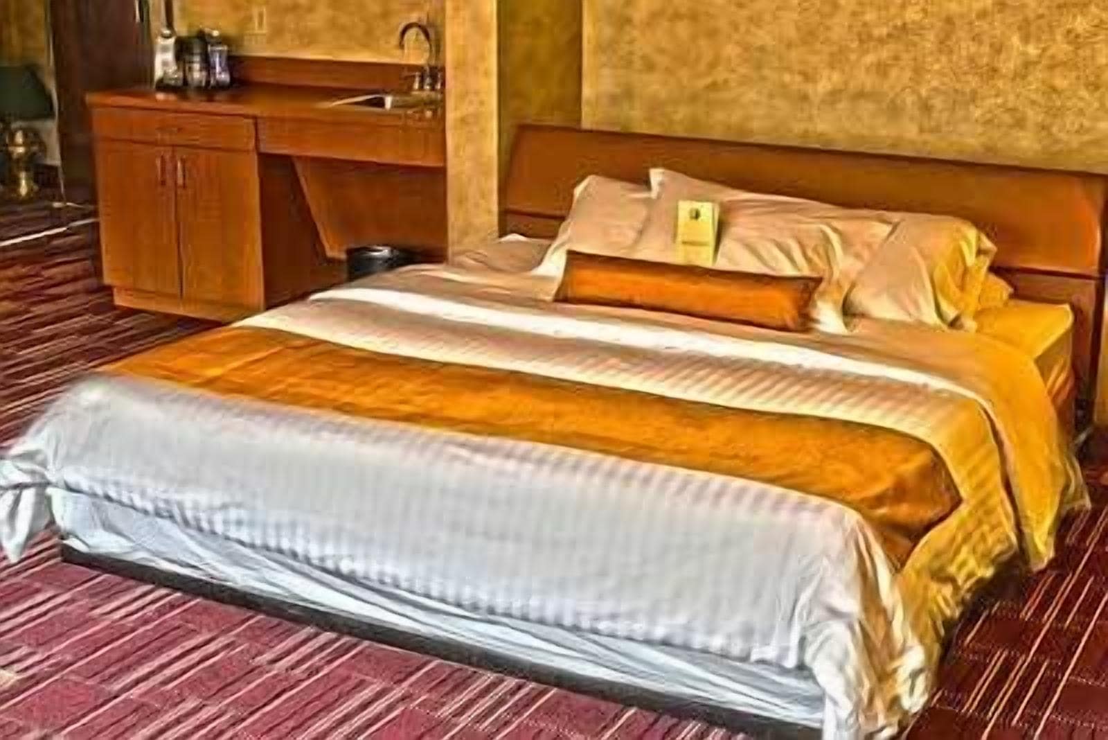 Una habitación de hotel con una cama, un aparador de madera y un lavamanos.