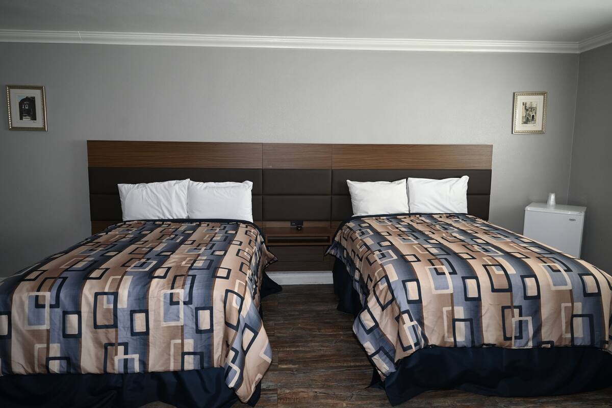 A double bed with a geometric patterned bedspread, a wooden headboard, and a bedside table with a lamp.