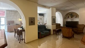 A spacious living area with a dining table, sofas, and a television. - Zion Hotel (Jerusalem)