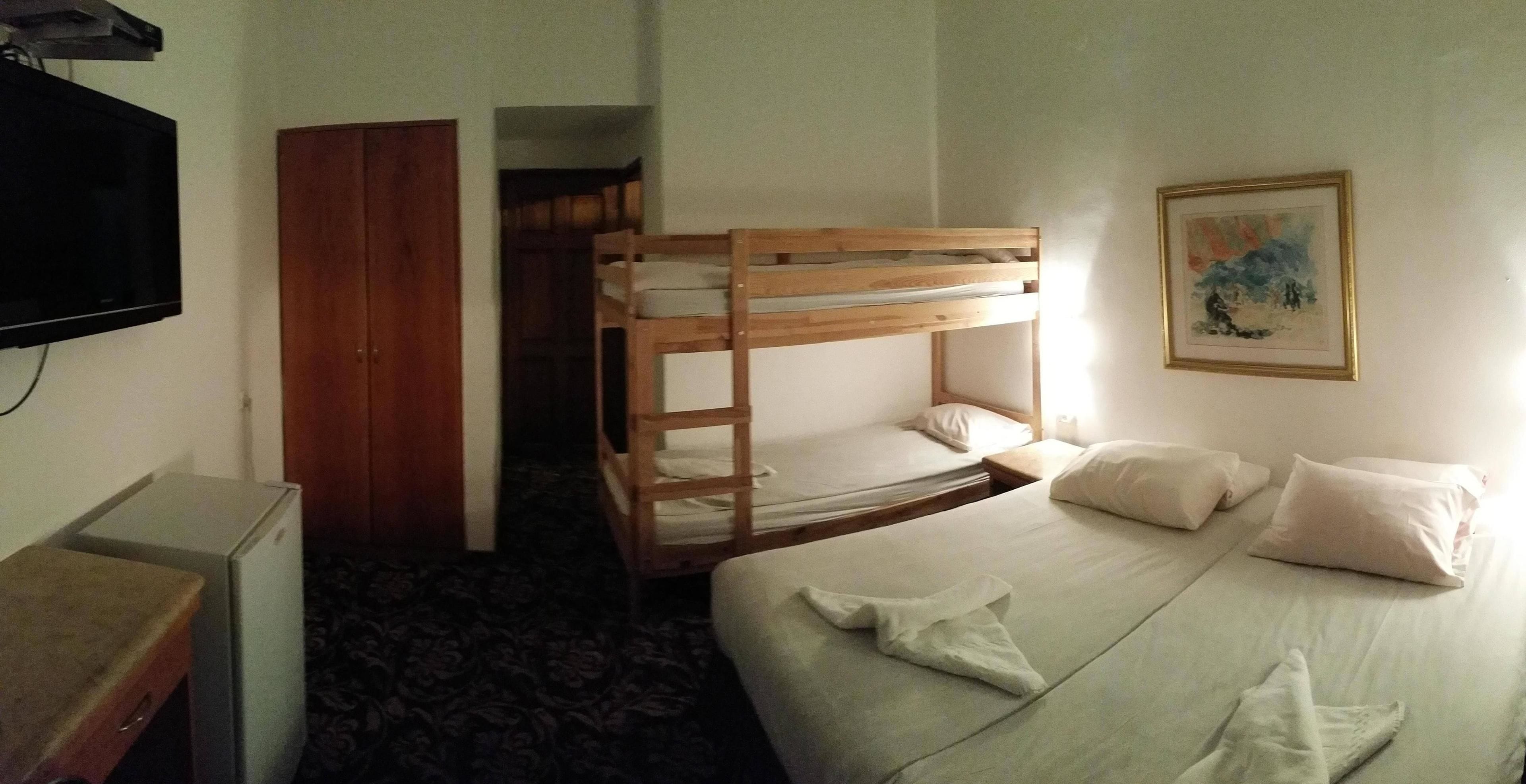Una habitación con literas, un televisor, un escritorio y un cuadro en la pared.
