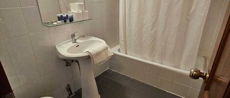 Un baño con inodoro, lavamanos, espejo y cortina de ducha.