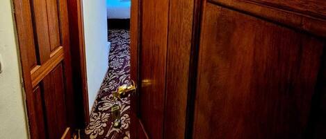 A wooden door with the number 306, leading to a room with a patterned carpet and a bed.
