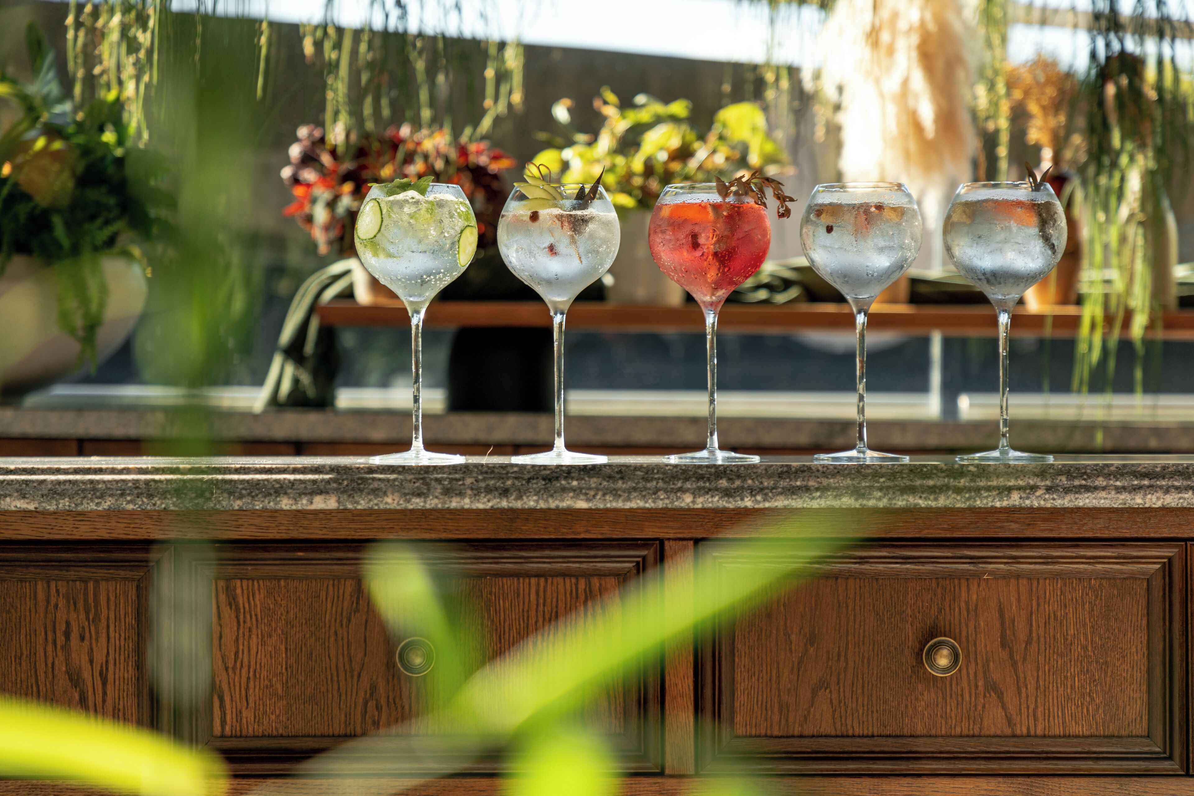 Una zona de bar con un mostrador de madera y una fila de vasos con diferentes bebidas.