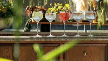 Una zona de bar con un mostrador de madera y una fila de vasos con diferentes bebidas.