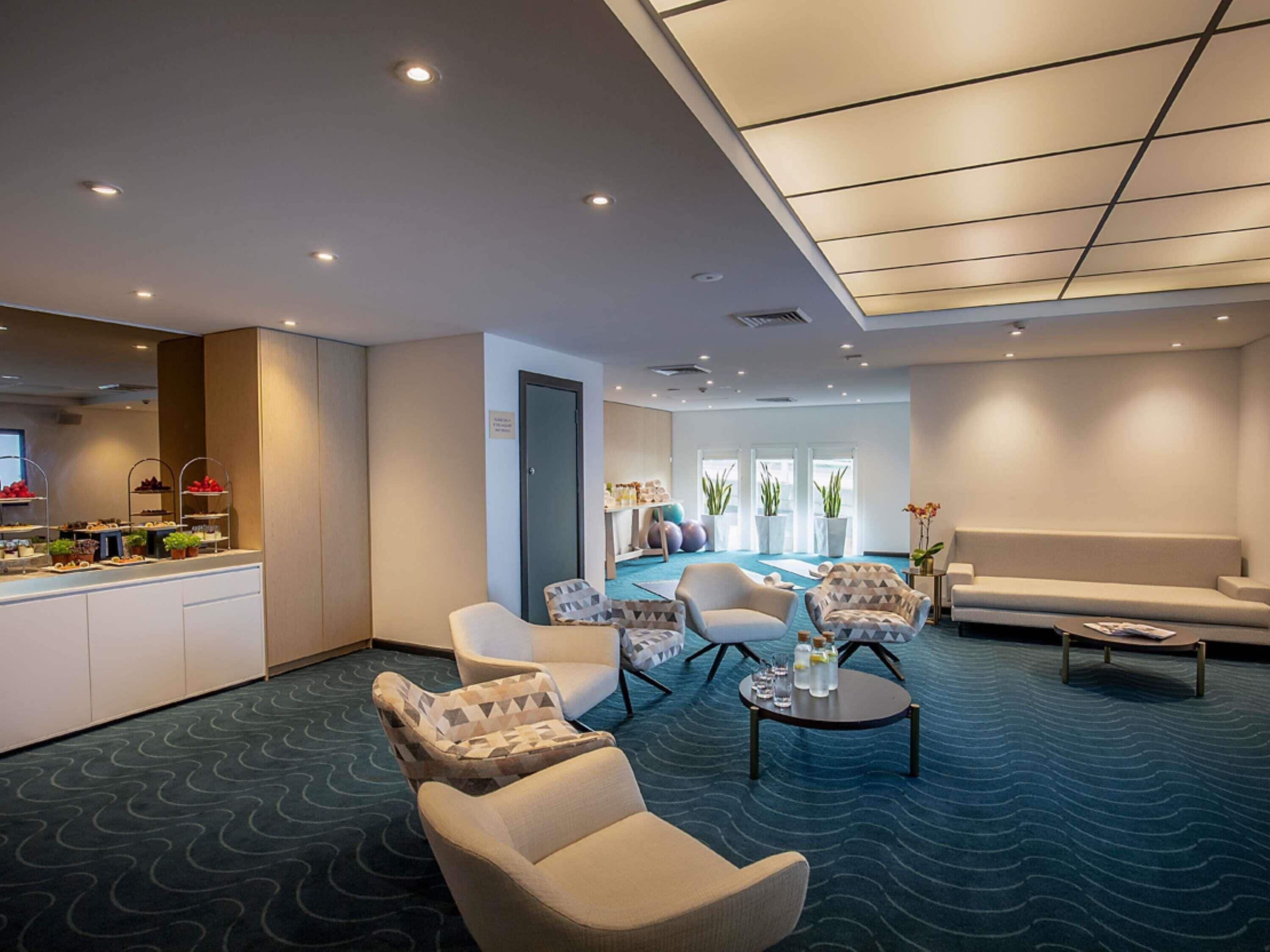 Un hall de hotel con mostrador de recepción, zona de estar y piscina.