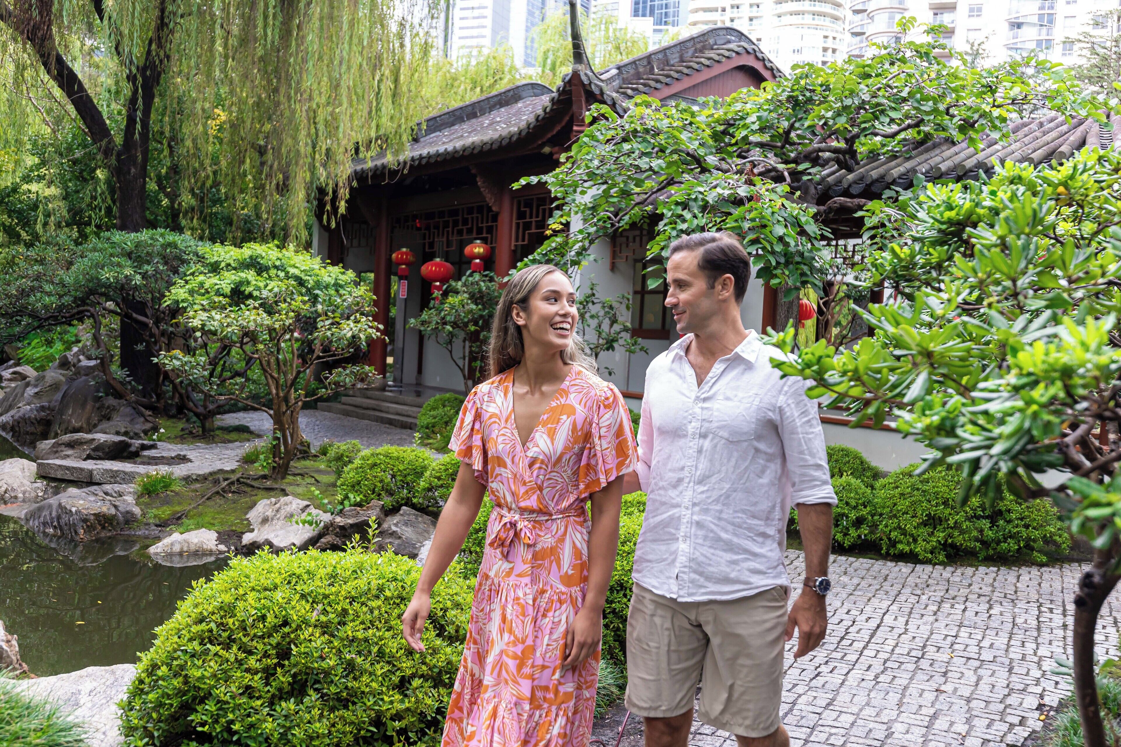 A traditional Chinese garden with a pond, rocks, and lush greenery.