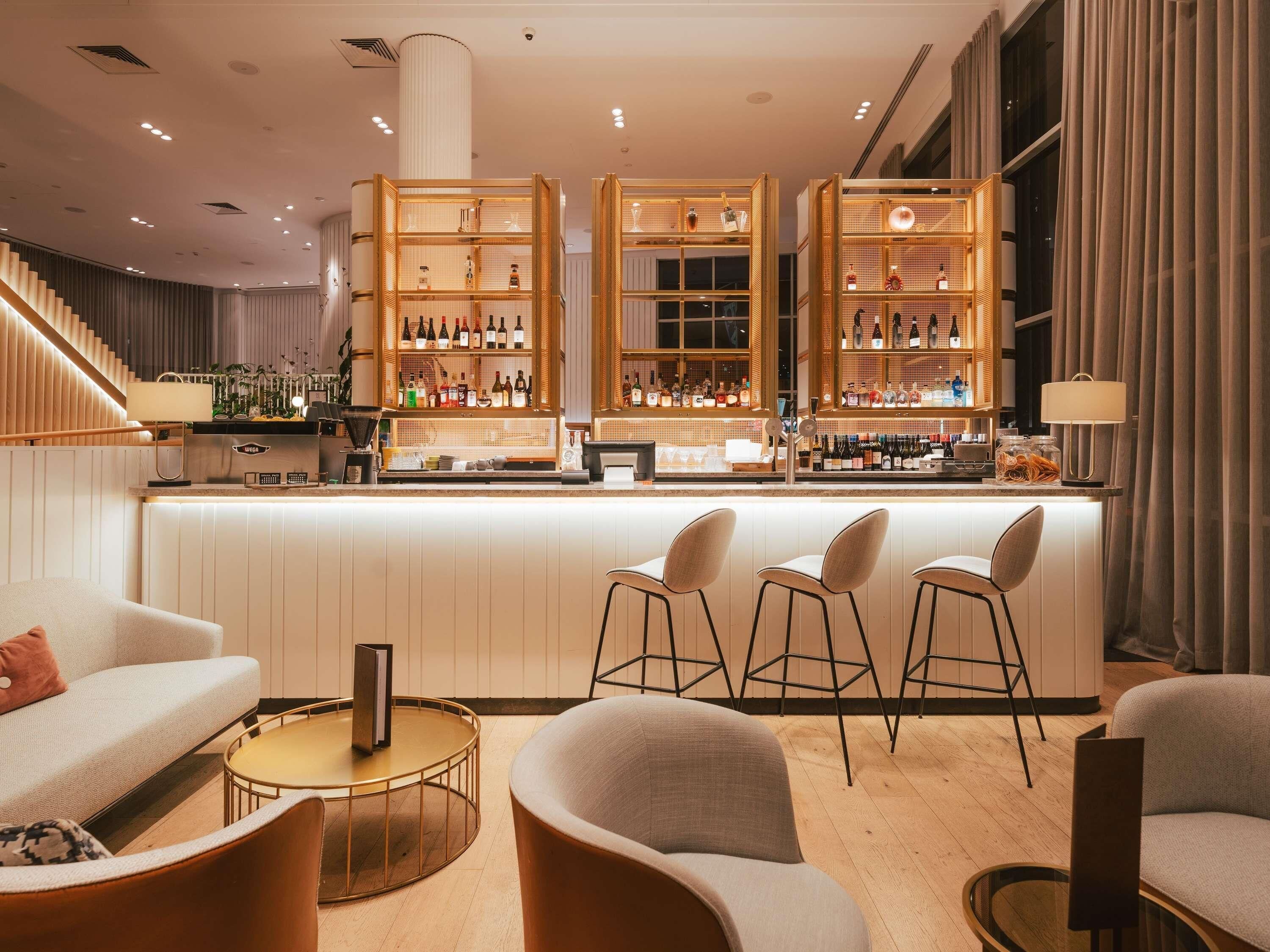 A bar area with a counter, stools, and shelves of bottles.
