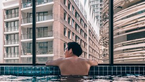 A man in a swimming pool with modern buildings in the background.