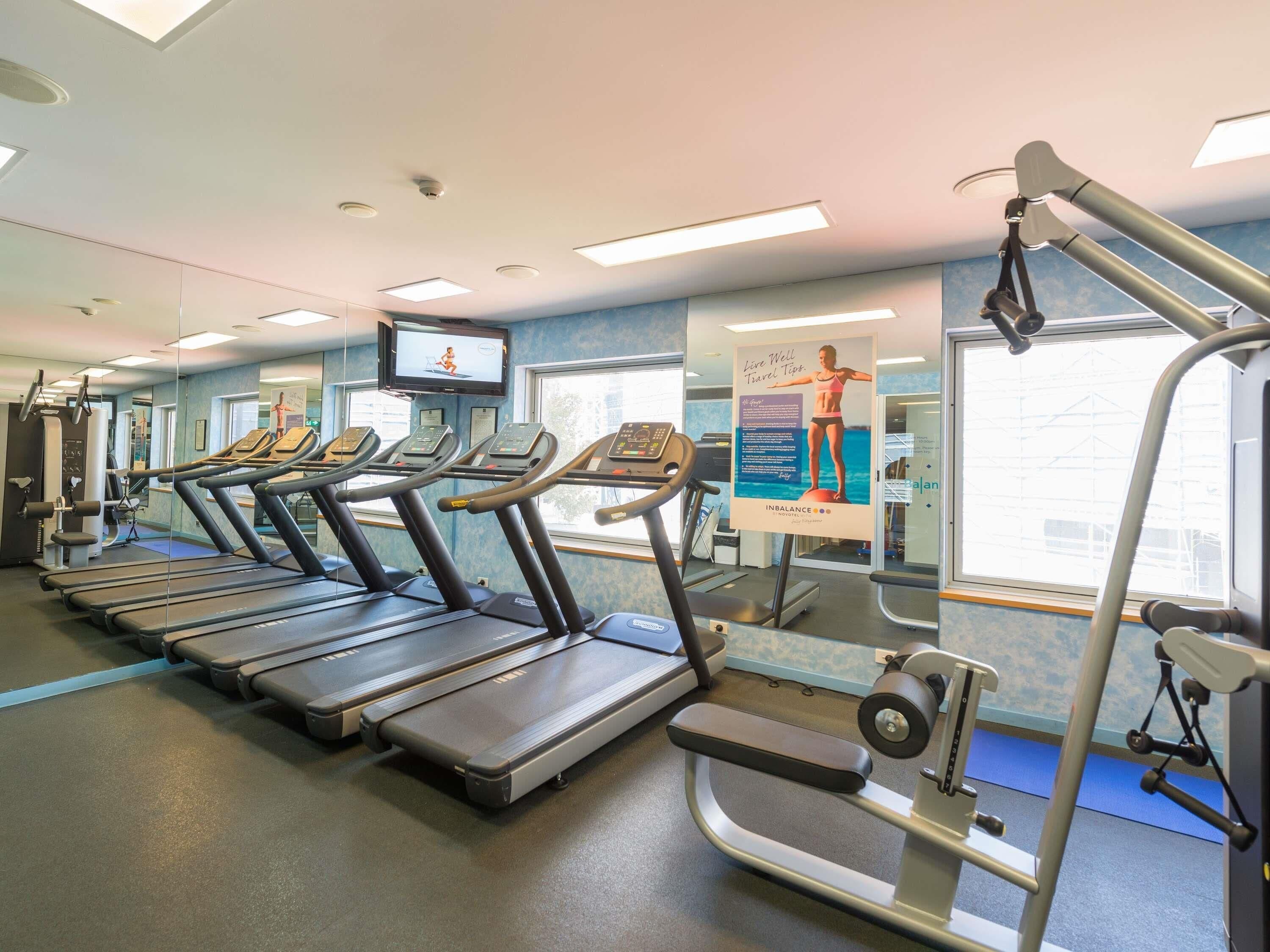 A gym with treadmills, a weight machine, and a TV screen.