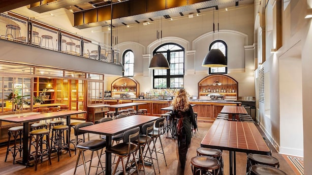 A spacious bar area with high ceilings, multiple seating arrangements, and a visible bar counter.