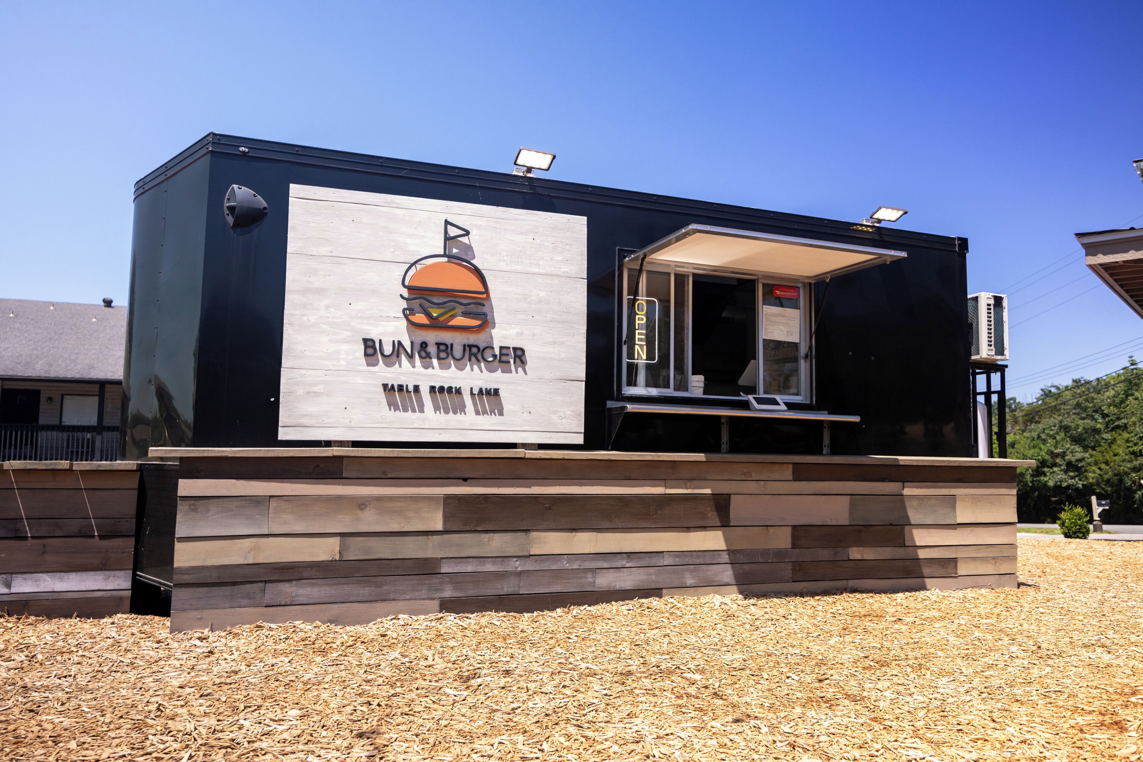 A building with a sign reading 'Bun & Burger' and a window indicating 'OPEN.'