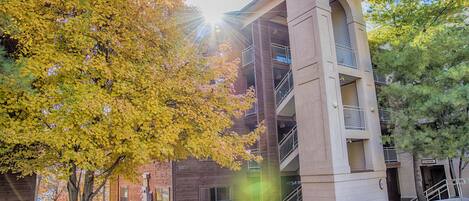 A multi-story building with a central courtyard, balconies, and a parking area.