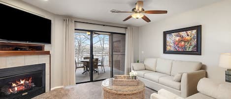 A living room with a fireplace, a sofa, a coffee table, and a ceiling fan.