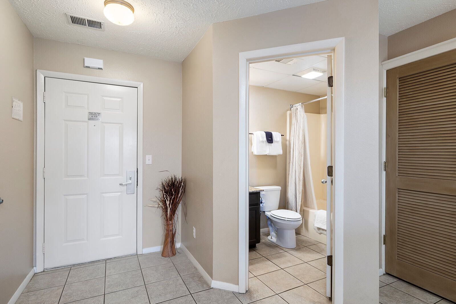 A hallway leading to a bathroom with a toilet, shower, and a door with a sign.